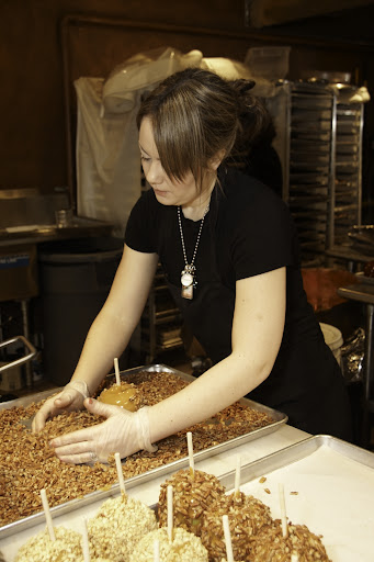 Immediately after the apple has been dunked, chocolatier Brittany Delcid covers it in nuts while it is still tacky. Amy’s roasts all of the nuts that are used as toppings.
