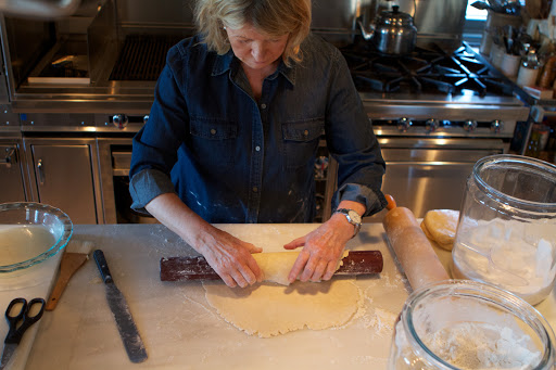 When the round of dough is the proper size, I like to use another rolling pin called a baton to roll the dough around.