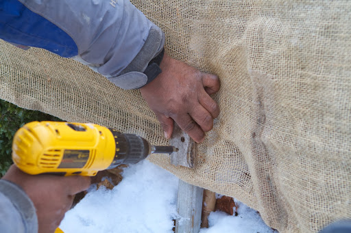 He sandwiched the burlap between a wooden strip and a wooden stake previously pounded into the ground.