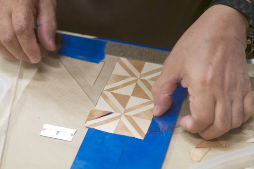 Marquetry is the art of applying thin slices of differently colored wood, shell, and other precious materials to create pictures and geometric designs.
