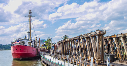 The red-hulled boat is a historic lightship called Frying Pan. Now docked at Pier 66 Maritime, it is one of 13 lightships remaining from more than 100 built. The US Coast Guard used lightships as floating lighthouses and to mark the entrances to harbors.