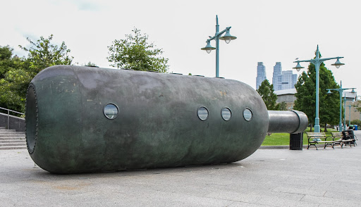 This sculpture, located at 55th at Pier 96 at Clinton, called Private Passage, was created by Malcolm Cochran. Made of bronze and zinc, this giant bottle contains a representation of an interior stateroom from the ocean liner, Queen Mary.