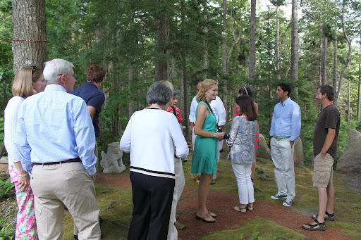 Guests gather near the counsel circle with Mike. The pathway is covered in pine needles.