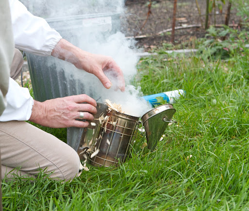 Before adding the hive top feeders, D.J. began by building a fire in the bee smoker. Here he added some pine shavings to create that smoke.