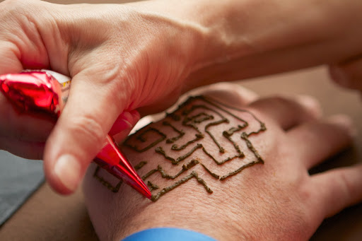 He decided on a labyrinth. The henna dye dries and when rubbed off, a tattoo remains, which can last for about two weeks.