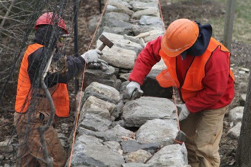 This style of wall is known as a dry stone wall. Dry stone is a method of building, in which structures are constructed from stones without any mortar to bind them together.