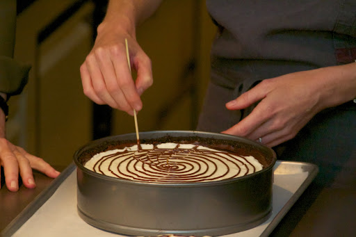 A spiderweb design on a no-bake cheesecake is made simply by piping chocolate in a spiral, and then dragging through with a skewer.