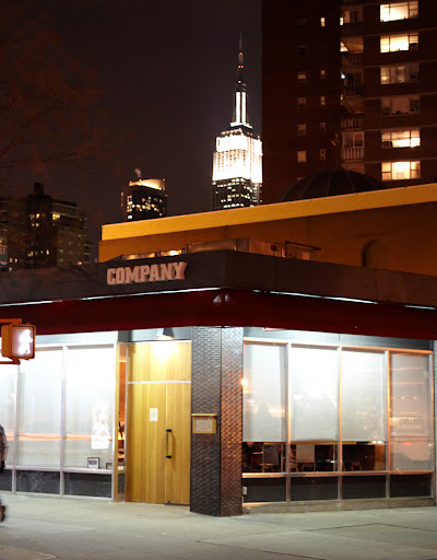 The exterior of Co. with the Empire State Building shining proudly in the background.