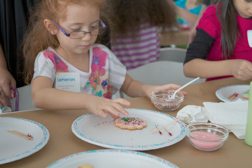 Cameron Rivera, daughter of HR and Payroll Operations Manager Lourdes Rivera adds colorful nonpareils to her flower shaped cookie