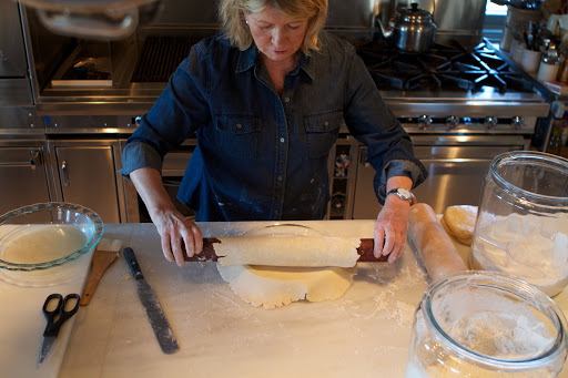 With the baton, I can pick up the round and transfer it to the pie dish. I place it over the dish and gently unroll the pastry.