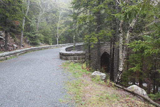 This is Hemlock Bridge, One of only two Gothic-arched bridges on the Rockefeller carriage road system. Built in 1924, it is one of eight major stone bridges on the Around-the-Mountain carriage road loop. The pointed arch design was chosen for its harmony with the pointed hemlock trees which surround the site.