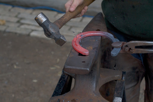 Linda pounds the glowing shoes on an anvil to draw two clips, which help keep the shoes in place. This kind of hammer is called a cross pein.