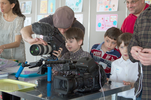Camera operator Philip Leaman teaches Walker Pace, Ethan Olko and Daniel Ward how to operate his Canon video camera