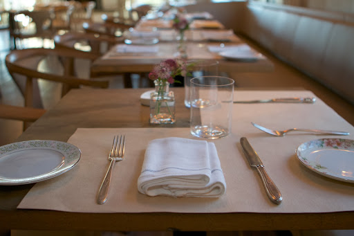 The tables are set with generous linen napkins and mismatched flatware and china - a very charming look.
