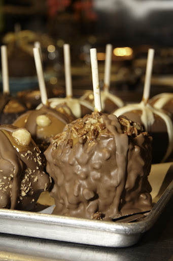 A variety of caramel apples are drying in the kitchen.