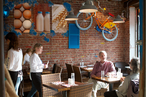 Layers of plaster were removed from the walls, exposing the bricks beneath. A bicycle hangs for decoration and the photos are the simple ingredients of traditional crêpe batter.