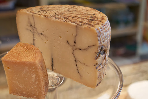 The larger cheese is Moliterno Black Truffle Pecorino, a raw sheep's milk cheese from Sardinia. The truffle paste is infused after the cheese has been aged so that it develops its own character before the truffles are injected.